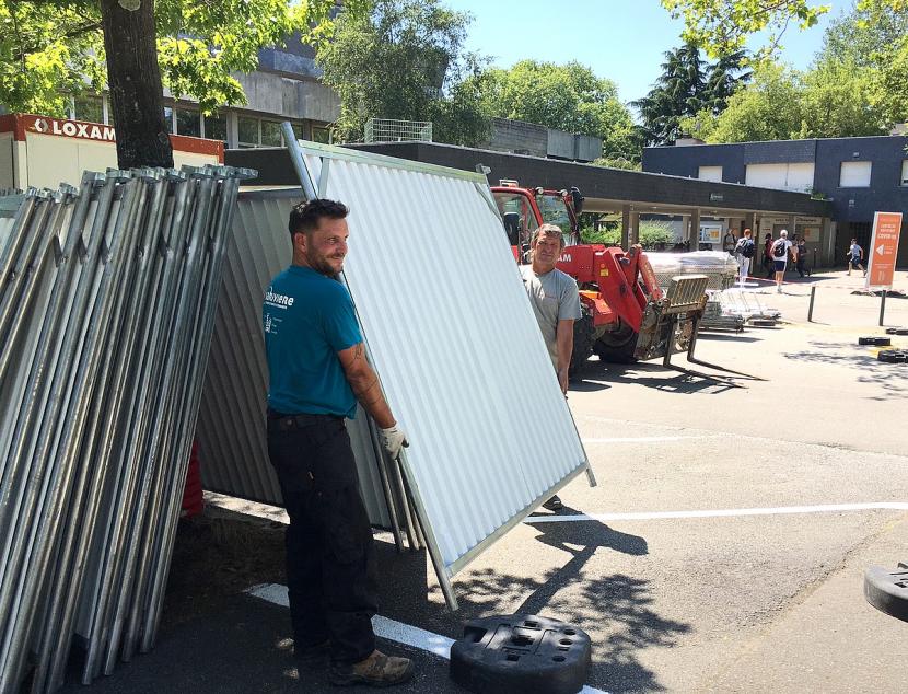 Ce lundi 19 juillet, une zone réservée au chantier est mise en place sur une partie des parkings et du cheminement piétonnier situés face à l'entrée de la piscine.